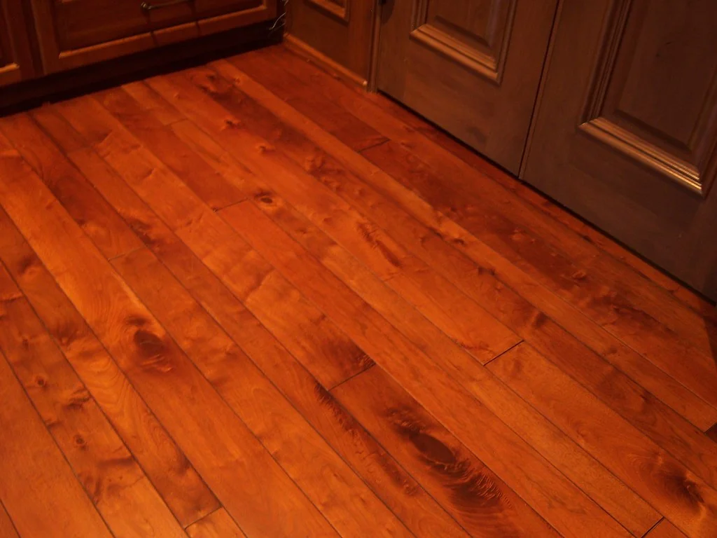 Warm-toned finished hardwood floorboards beside a doorway