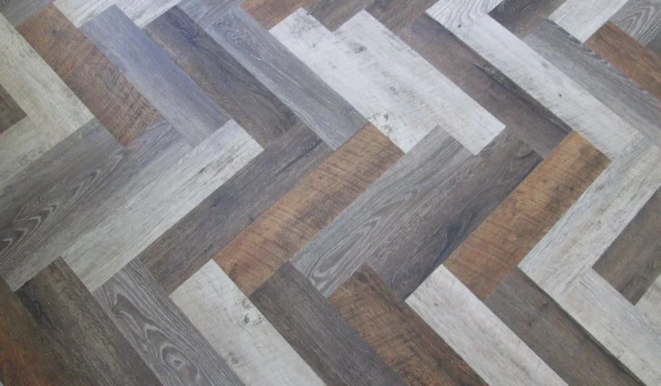Multi-tone grey wood-look luxury vinyl planks laid in a herringbone pattern
