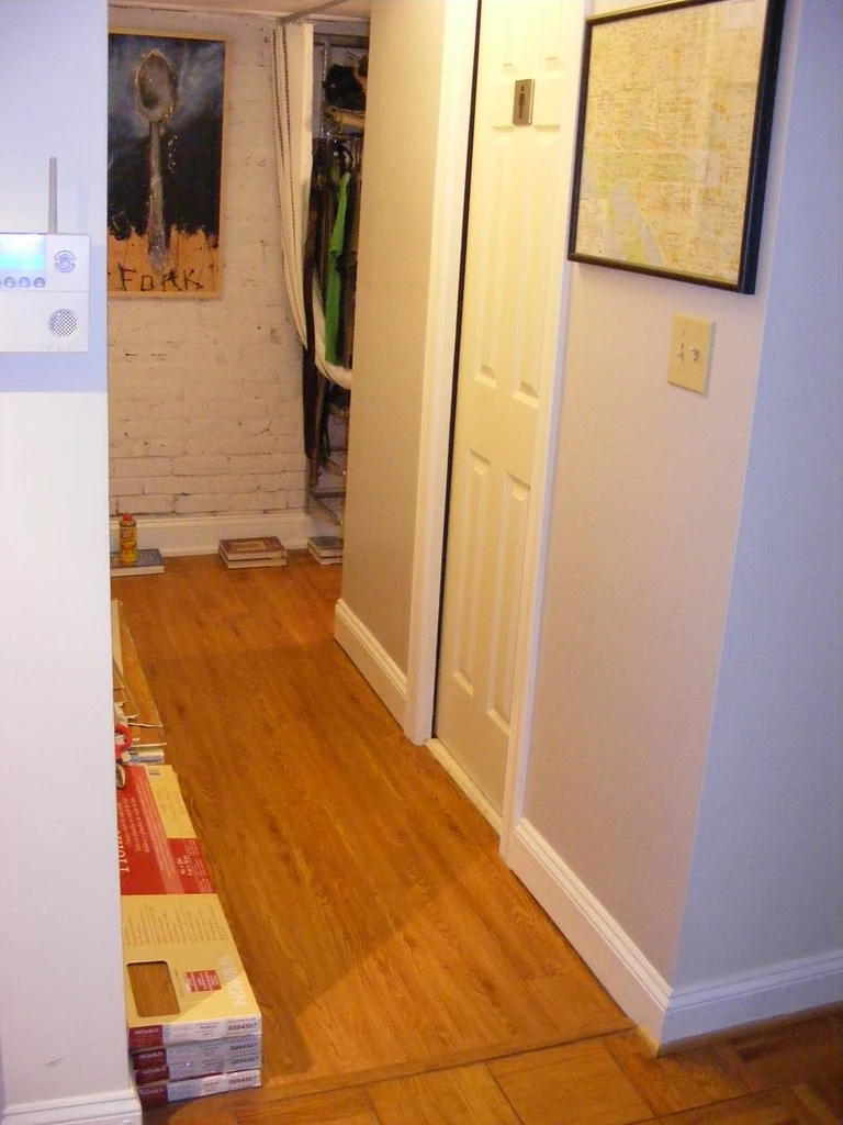 Vinyl plank flooring mid-install in a hallway with boxes of planks nearby